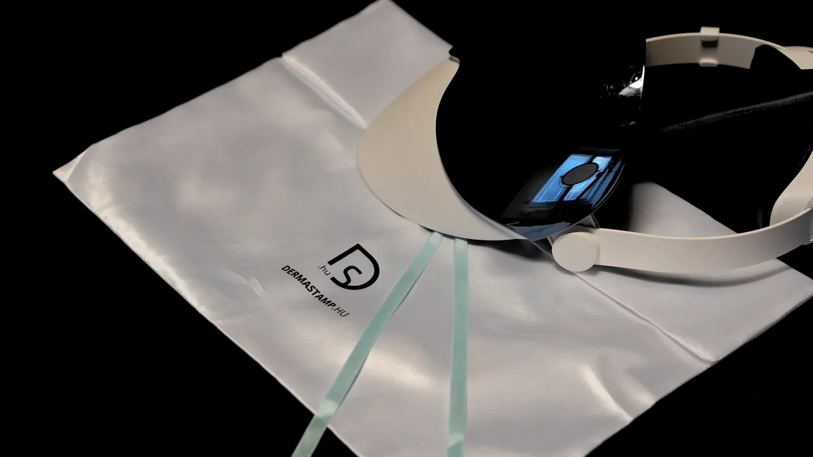 Den vita satinpåsen med dermastamp.hu-logga, med den hopfällda masken på